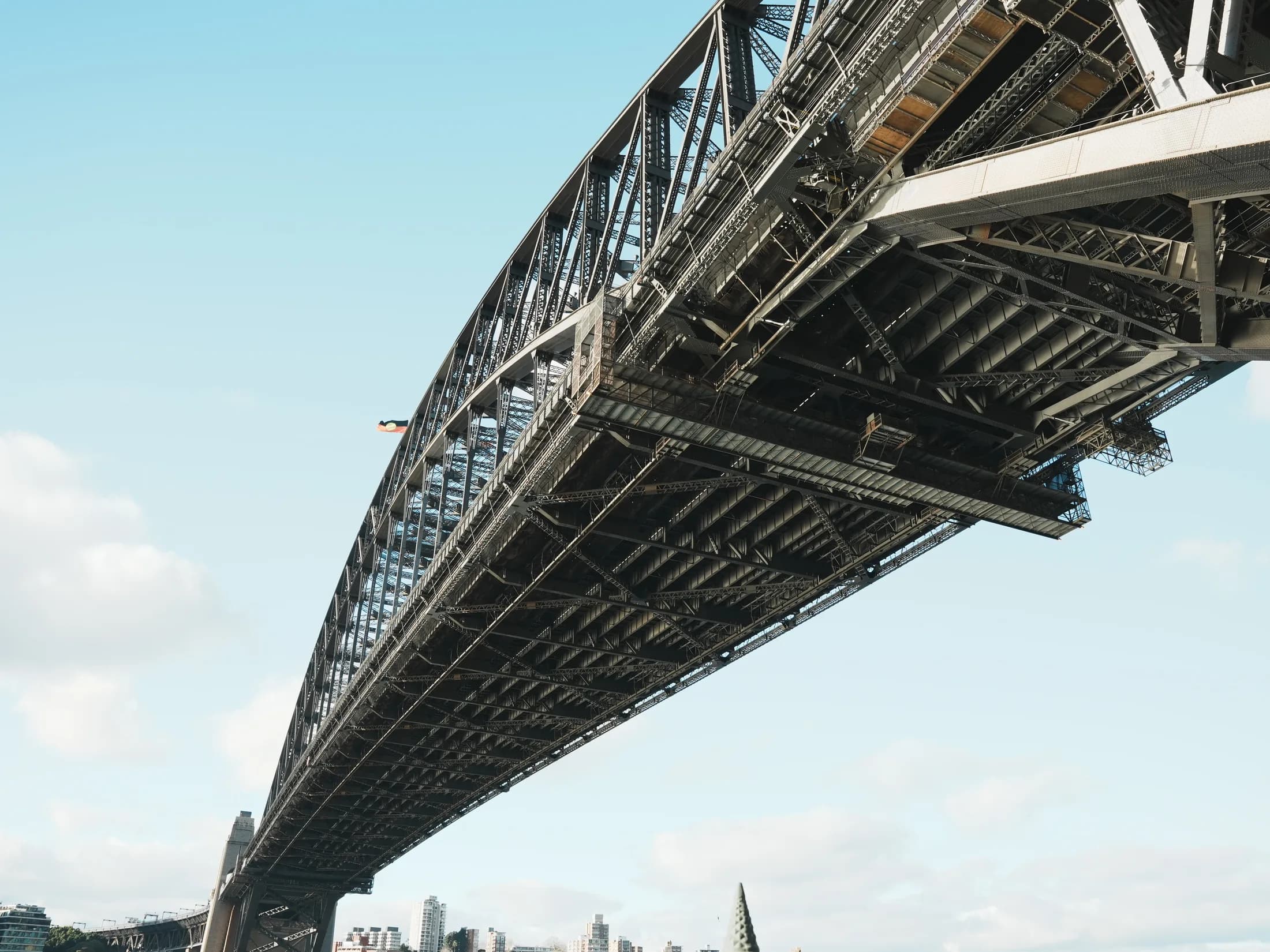 Looking up at the underside of the Sydney Harbour Bridge against a clear sky