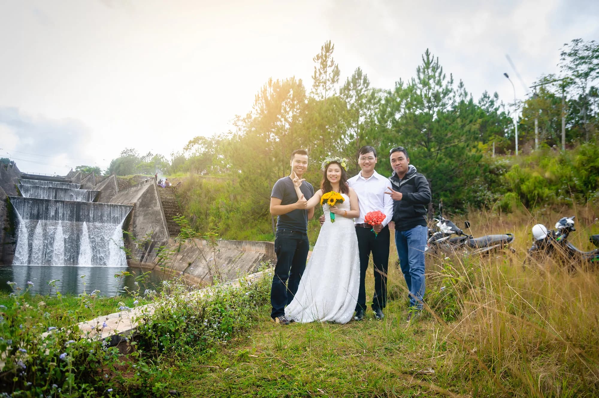 A wedding couple posing with two groomsmen in front of a waterfall
